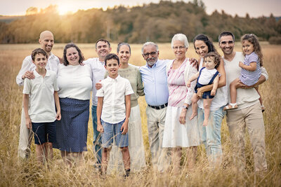 familjebild på 3 generationer med hela familjen  motljus i högt gräs
