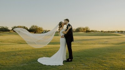 bride and groom share a kiss in a field