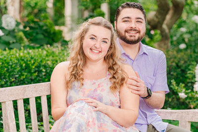 A smiling couple sitting on a bench in Airlie Gardens enjoying their destination wedding photos