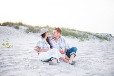 couple sitting on the beach with a flannel shawl over their shoulders and sandy toes
