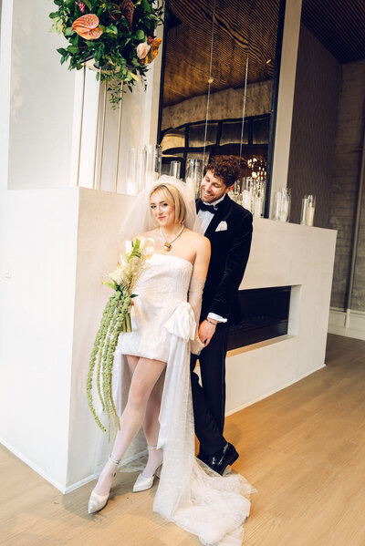 A bride and groom in a white wedding gown and gray suit staring into each other’s eyes.