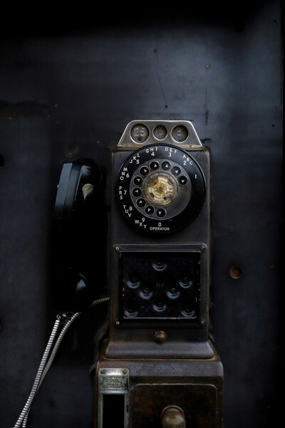 An old rotary payphone with coin slots for quarters, dimes, and nickels.