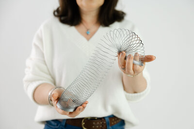 Woman holding silver slinky symbolizing flexibility and nervous system resilience
