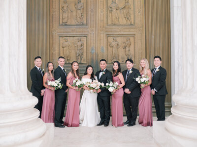 A bride, groom and their wedding party pose in front of the US Supreme Court