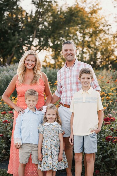 A joyful family standing together in a sunlit flower field, showcasing love and connection.