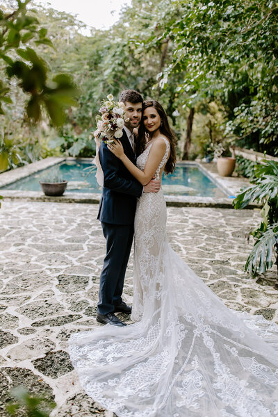 M&C In front of a pool holding each other.