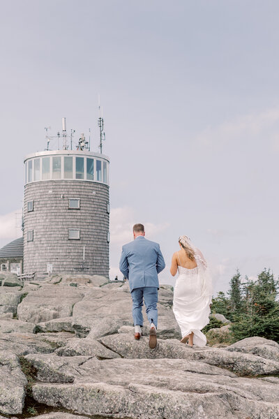 Light and airy photograph of a couple holding hands and walking during their elopement in the Adirondacks near Lake George. It was peak fall foliage on their elopement day in Upstate NY.
