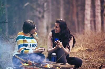 Two women talking around a campfire