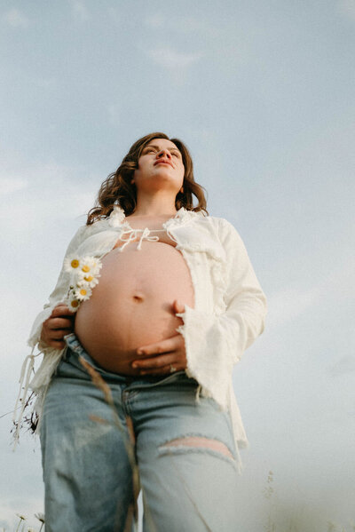 Pregnant mother posing outdoors, showcasing her baby bump in a candid maternity photo, captured by an Oregon photographer for a timeless and natural look.