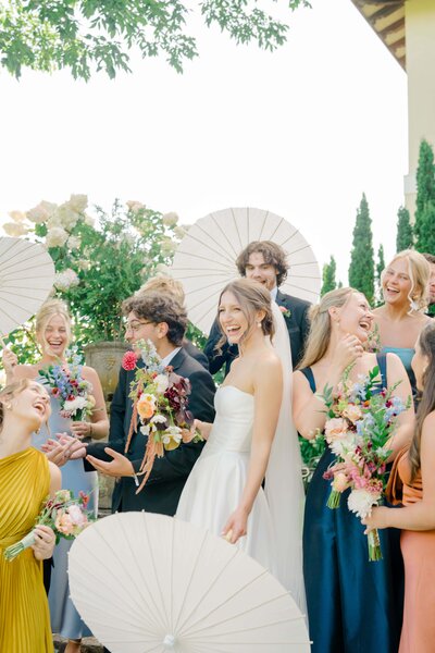 Fun and vibrant bridal party portrait at Aldworth Manor in New Hampshire, featuring the bride surrounded by her joyful bridesmaids, all holding colorful bouquets and parasols. This lively and heartfelt moment captures the connection and celebration of love at the wedding. Felisha, a New England-based destination wedding photographer, captures timeless wedding moments in New Hampshire, New England, and worldwide locations.