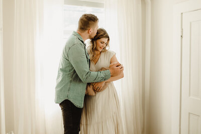 A couple stands holding and admiring their newborn baby, photographed inside their Vancouver Washington home.