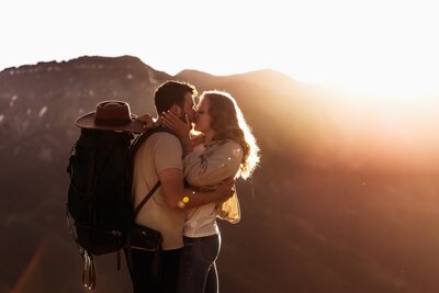 Shannon Lee, a Colorado elopement photographer capturing a romantic moment between a couple sharing a kiss at sunset with breathtaking mountain views in the background.
