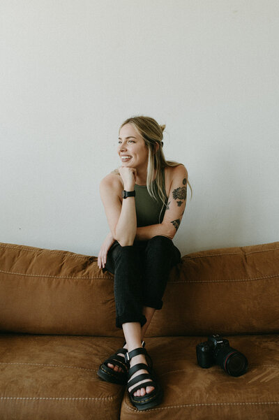 woman sitting on a couch with her head resting in her hand while smiling