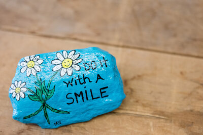 Blue painted rock with the words "Do it with a smile"