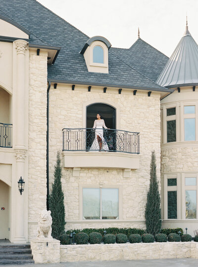 A bride standing on the balcony of Little Elm wedding venue Knotting Hill Place