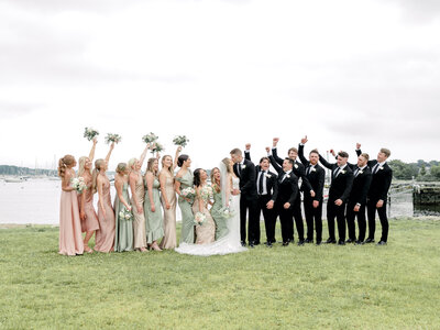 Empty ceremony space with white chairs and white flower arrangements with the ocean in the background