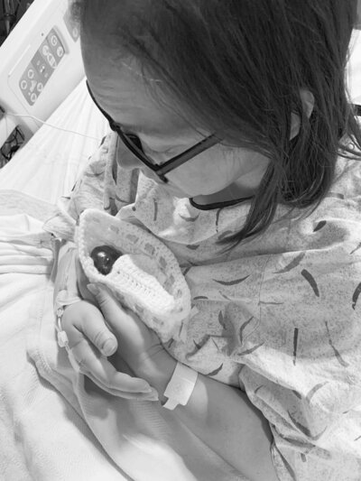bereaved mother holds stillborn baby in crochet cradle