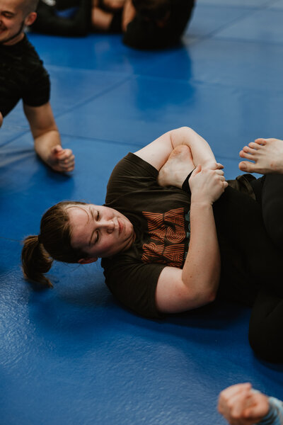 Woman applying a foot lock in no gi class at IRONGRIP jiu jitsu