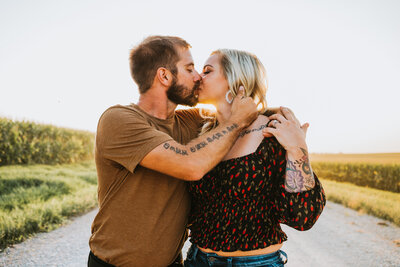 engaged couple kissing in the middle of a gravel road by Iowa City wedding photographer Sabrina Wilham