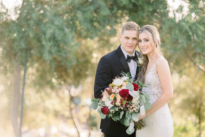 Bride and Groom lean into each other as they pose for a wedding photo