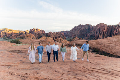 family walking on the red rocks in snow canyon utah and laughing together during family photos