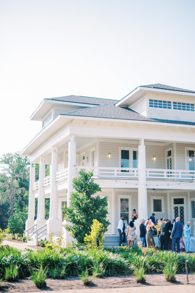 Exterior image of a large white wedding venue with guests outside
