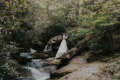 newlyweds stand near creek