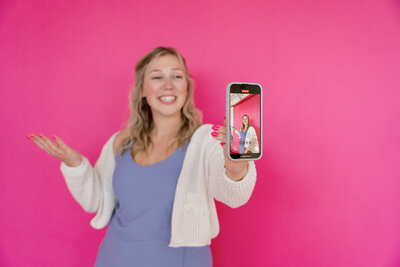Kat holding up a fork in front of a small cake with pink and yellow icing