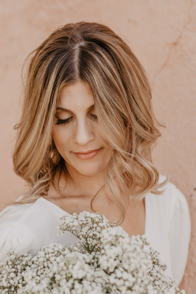 young bride with caramel hair poses with her wedding bouquet looking down at the florals, captured by Jackson Hole wedding photographer
