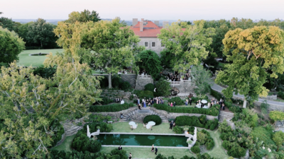 Aerial photo of garden venue, features a small fountain, trees and people walking 