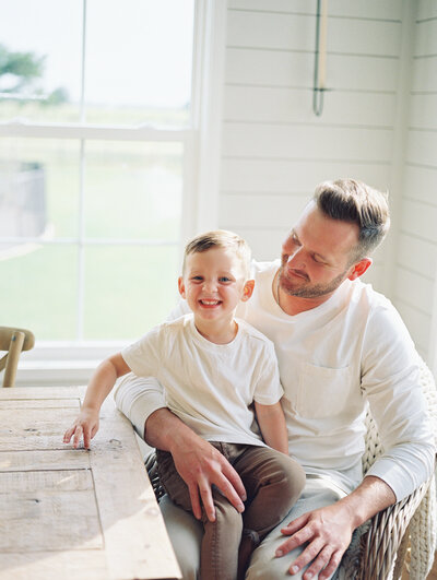 Little boy smiling while sitting in dad's lap