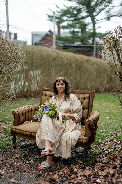 Pittsburgh wedding florist Heavenly Blooms sitting on a couch outdoors holding a floral arrangement