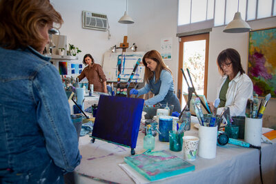 group of people smiling and holding paintings they painted