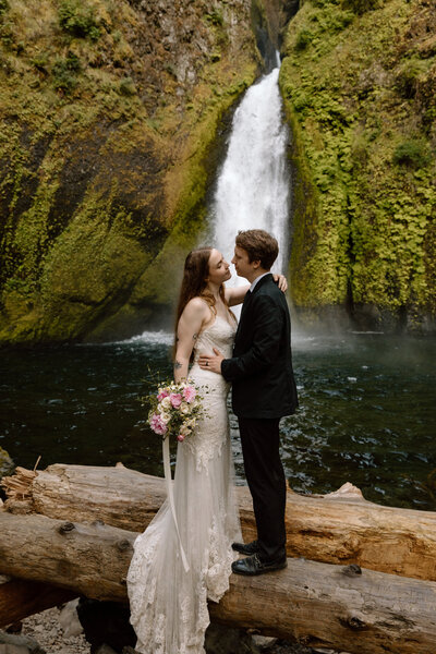Bride and groom standing on a log in the Columbia River Gorge.