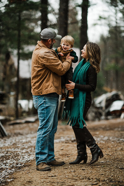 Young family smiling for photo in beautiful Wisconsin woods during fall.
