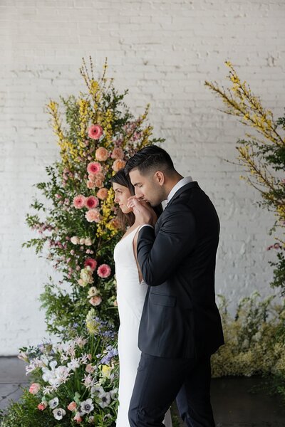 Bride and groom walking past flower arch planned by brooklyn wedding planners at Helena Elizabeth Events