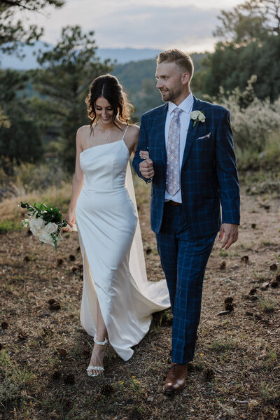 Bride and groom walk together during Colorado mountain Airbnb microwedding.