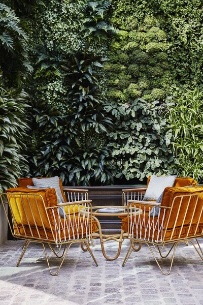 Outdoor lounge area with green wall and funky retro furniture designed by Soho House Henriette Kockum
