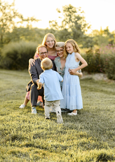 Parents surrounded by their three smiling young children during a golden-hour family session captured by a Kansas City family photographer.