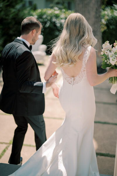 low back wedding gown with long sleeves, bride and groom walking on the rooftop of the international spy museum in washington dc photographed by dc wedding photographer omar & comany