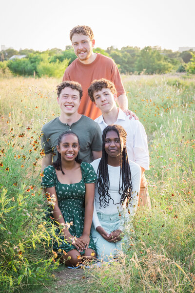 five sibling posing together in a field