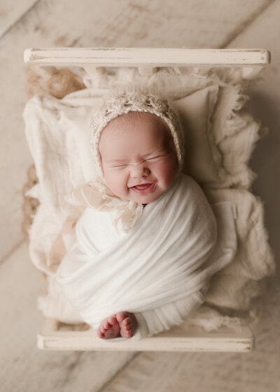 newborn baby smiling for her photo session in Oswego, ny.