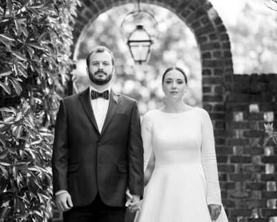 A wedding couple holding hands and looking forward.