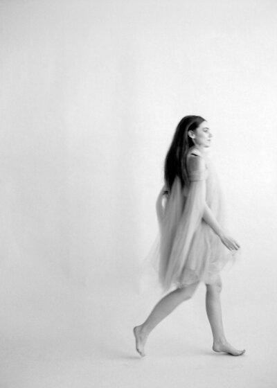 Black and white portrait of a woman walking in front of draped fabric at Studio by Pepper June in Castle Hill, Sydney's Hills District.