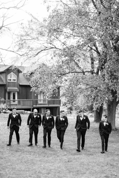Black and white candid of groom and groomsmen walking on wedding morning in Caledon, photographed near Toronto