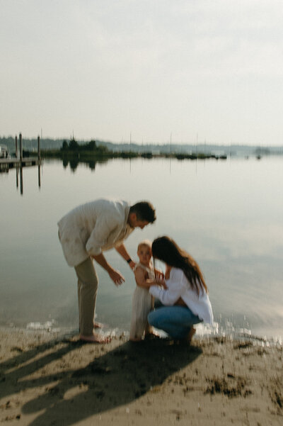 mom dad and daughter on the beach in the ocean during family photography session
