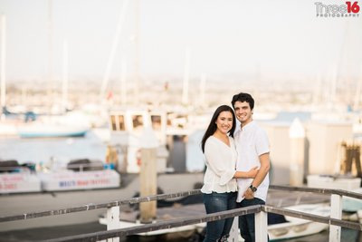 Engaged couple pose on the harbor docks at the Balboa Fun Zone