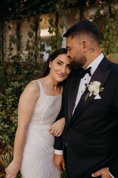 Auckland Wedding Photographer - photo of bride and groom standing in front of a greenery wall 