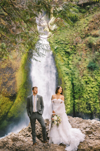 Bride and groom standing in front of an Oregon waterfall