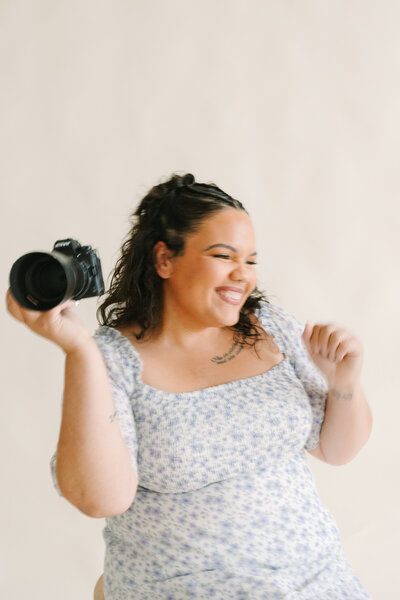 A photographer smiling with a camera in one hand